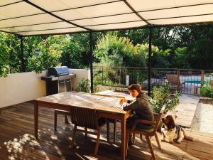 a woman sitting at a table with a dog on a deck at Villa Roquefortoise avec piscine in Roquefort-les-Pins