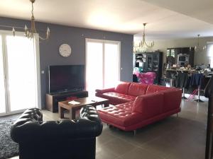 a living room with a red couch and a tv at Villa Roquefortoise avec piscine in Roquefort-les-Pins