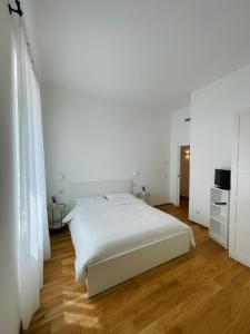 a white bedroom with a white bed and wooden floors at A un passo dalla piazza in Ascoli Piceno
