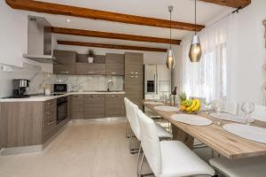 a kitchen with a wooden table and white chairs at Villa Antani with heated pool, sauna & jacuzzi in Crikvenica