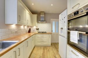 a white kitchen with white cabinets and a sink at The Dudley House I Spacious Executive House with Big Kitchen, Dining Space and Garden in Castle Quarter I eco-Short Term Let by SILVA in Bedford