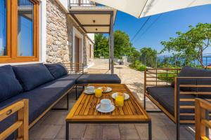 a patio with a blue couch and a wooden table at Villa Antani with heated pool, sauna & jacuzzi in Crikvenica