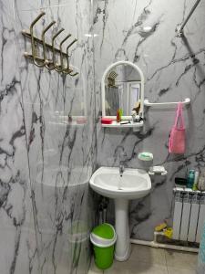 ein Marmorbad mit einem Waschbecken und einem Spiegel in der Unterkunft Guest house Family7 in Osch