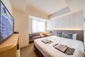 a hotel room with a bed and a flat screen tv at Keio Prelia Hotel Kyoto Karasuma-Gojo in Kyoto