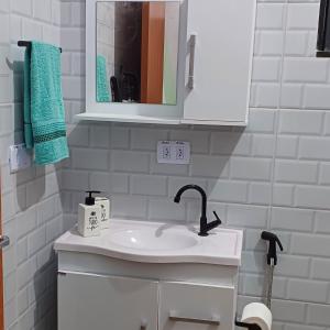 a white bathroom with a sink and a mirror at Apê Estúdio Rodrigues 02 in Paranaíba