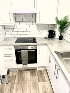 a white kitchen with a stove and a sink at Flat in London- Modern 2 Bedroom Apartment Harrow near Wembley in Harrow