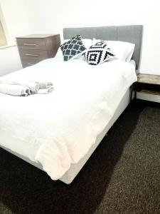 1 cama grande con sábanas blancas y almohadas. en Flat in London- Modern 2 Bedroom Apartment Harrow near Wembley, en Harrow