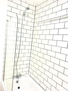 y baño con ducha y pared de azulejos blancos. en Flat in London- Modern 2 Bedroom Apartment Harrow near Wembley en Harrow