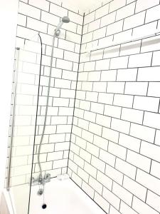 a bathroom with a shower with a white tiled wall at Flat in London- Modern 2 Bedroom Apartment Harrow near Wembley in Harrow