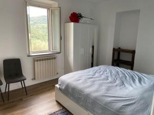 1 dormitorio con 1 cama, 1 silla y 1 ventana en L'Ortensia, en Cibottola