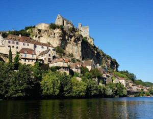 a town on top of a mountain next to a body of water at Sarrasins Bed and Breakfast in Beynac-et-Cazenac