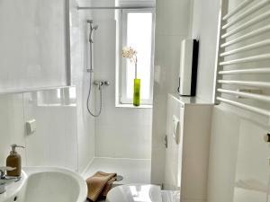 baño blanco con ducha y lavamanos en Design Apartment - Parking - Kingsize-Bett - 2x Bad - Zentrum en Hannover