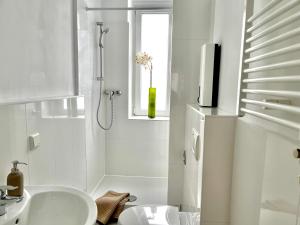 baño blanco con ducha y lavamanos en Design Apartment - Parking - Kingsize-Bett - 2x Bad - Zentrum, en Hannover