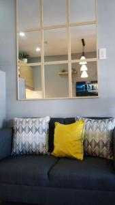 a blue couch with a yellow pillow and a mirror at THE FIKA ROOM near MNL Airport - Scandi Studio Unit with Fast Wi-Fi & Netflix - Read Full Property Desc before booking in Manila
