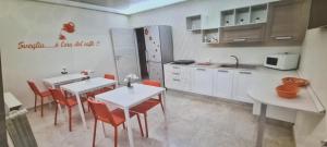 cocina con 2 mesas y sillas rojas en B&B Uliveto, en Cerignola