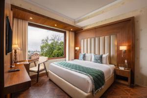 a bedroom with a large bed and a window at WelcomHeritage Grand, Srinagar in Srinagar