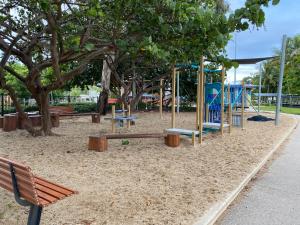 a park with a playground with benches and a tree at Haven Guesthouse in Holloways Beach