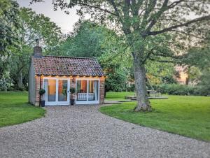 a small cottage in a park with a tree at The Old Forge in Bishop Wilton