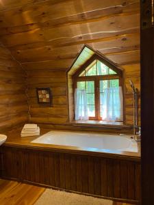 a large bath tub in a wooden room with a window at Lisotel in Rokytne