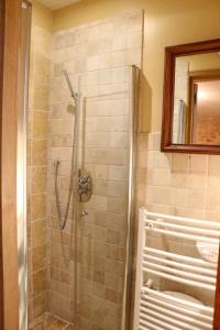 a shower with a glass door in a bathroom at Les Perroutis in Saint-Alvère