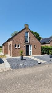 um edifício de tijolos com uma varanda e uma entrada em Vakantiewoning Maas en Waal 195 em Ewijk