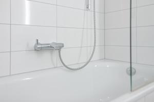 y baño de azulejos blancos con ducha y bañera. en Lieblingsnest im Plaza Hotel, en Timmendorfer Strand