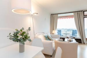 sala de estar con muebles blancos y ventana grande en Lieblingsnest im Plaza Hotel, en Timmendorfer Strand