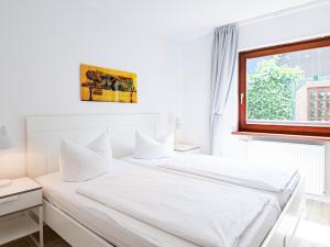 two beds in a white room with a window at Lieblingsort Lachen in Timmendorfer Strand