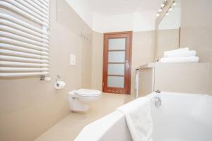 a white bathroom with a toilet and a bath tub at InPoint 2-bedrooms Apartment with private garden and free parking in Krakow +20 photos
