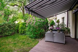 a wooden deck with plants and a black awning at InPoint 2-bedrooms Apartment with private garden and free parking in Krakow