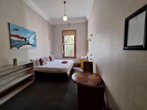 een slaapkamer met een bed, een tafel en een raam bij Ashanti Lodge Backpackers in Kaapstad