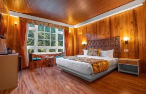 a bedroom with a bed and a desk and a window at Summit Gangchen Hotel in Lachen
