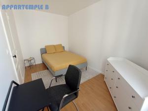 um pequeno quarto com uma cama, uma secretária e uma cadeira em Appartemple em Meaux
