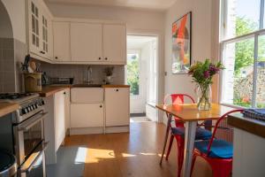 una cocina con armarios blancos y una mesa con sillas. en Stylish two bedroom terrace with garden en Ramsgate