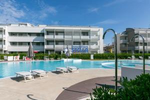a swimming pool with chairs and a building at Laguna Park in Lido di Jesolo
