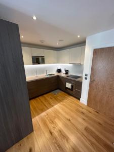 uma grande cozinha com pisos em madeira e armários brancos em Colindale luxury Apartment em Colindale