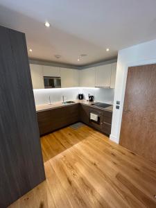 a large kitchen with wooden floors and white cabinets at Colindale luxury Apartment in Colindale