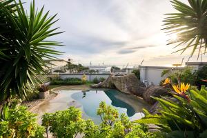a swimming pool with a rock in a garden at Sir Roys Guesthouse At The Sea in Port Elizabeth