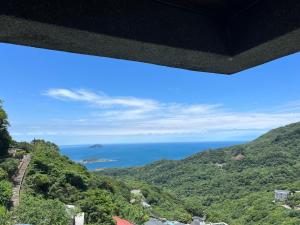 einen Blick auf das Meer von einem Berg aus in der Unterkunft Slowly B&B in Jiufen