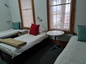 a room with two beds and a table and a window at Ashanti Lodge Backpackers in Cape Town
