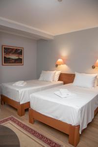 two beds in a room with white walls at Arber Hotel in Tirana