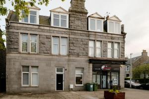 an old stone building with white windows on a street at West End Retreat - SJA Stays in Aberdeen