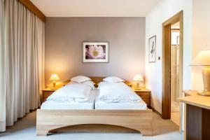 a bedroom with two beds and two lamps on tables at Marini's giardino Hotel in Tirolo