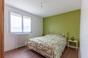 Dormitorio verde con cama y ventana en Gîte Renardeau - Maison à deux pas du centre ville, en Carentan