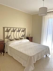 una camera da letto con un grande letto e un copriletto bianco di Villetta Paestum a Mattine