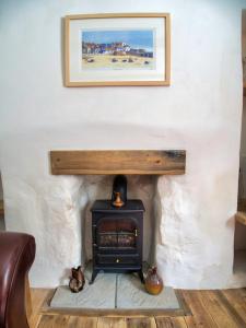a fireplace in a room with a picture on the wall at Knocker Cottage is a 3 bedroom made up of 1 double bedroom and 2 small double bedrooms in small village 10 min to beaches in Camborne