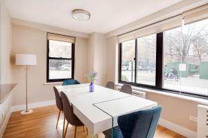une salle à manger avec une table blanche, des chaises et des fenêtres dans l'établissement 3 BR in Upper West Side, à New York