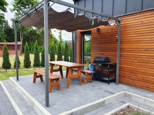 een picknicktafel en banken onder een parasol op een patio bij Domek na Polanie in Ustroń