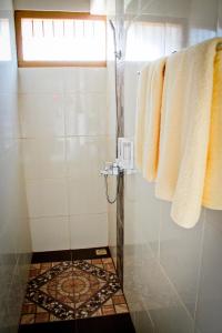 y baño con ducha y suelo de baldosa. en Bamboosa, en Bukittinggi