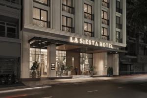 La Siesta Premium Saigon في مدينة هوشي منه: مبنى عليه لافته مكتوب عليها فندق لا سيستا